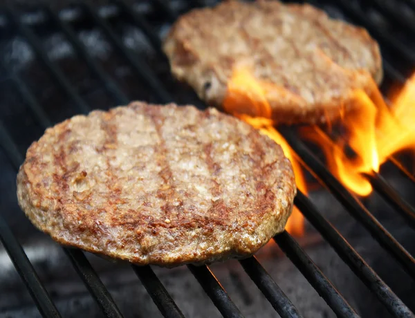 Lédús marha hamburgerek, sistergő forró lángok a barbecue felett — Stock Fotó