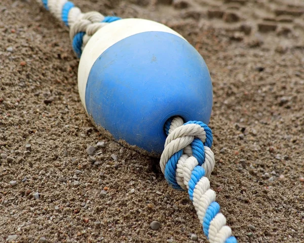 Blue and white plastic BUOY laying on sand at beach — Stock Photo, Image
