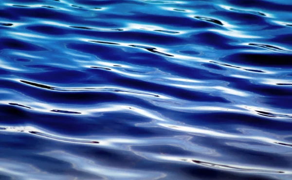 Ondulaciones suaves que se mueven a lo largo de la superficie de aguas azules profundas —  Fotos de Stock