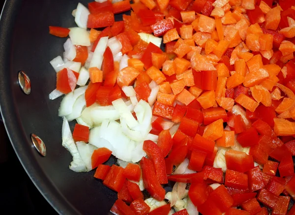 Pimientos rojos cortados en cubitos, zanahorias y cebollas en una sartén antiadherente lista para cocinar —  Fotos de Stock
