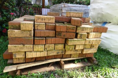 İnşaat için istiflenmiş kırmızı kil tuğlaları kapatın. Tuğla endüstriyel üretimi. 