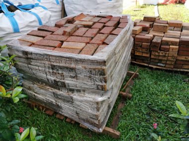 İnşaat için istiflenmiş kırmızı kil tuğlaları kapatın. Tuğla endüstriyel üretimi. 