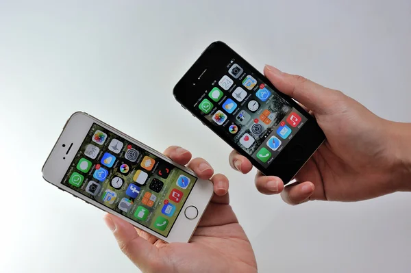 Woman holding white Apple iPhone 5S & black Apple iPhone 4S — Stock Photo, Image