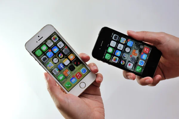 Mujer sosteniendo blanco Apple iPhone 5S y negro Apple iPhone 4S — Foto de Stock