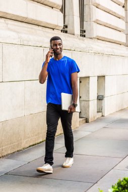 New York 'ta okuyan genç Afrikalı bir üniversite öğrencisi. Mavi tişört, siyah pantolon, beyaz spor ayakkabı, dizüstü bilgisayar, cep telefonuyla konuşmak, ofisin dışında sokakta yürümek.