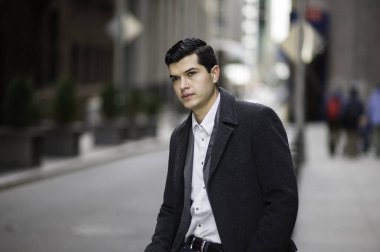 Genç bir işadamı bir caddenin kenarında oturuyor ve derin derin düşünüyor.