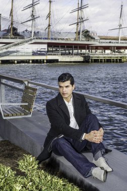 Genç bir işadamı nehir kenarında oturuyor ve derin derin düşünüyor..