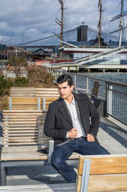 Genç bir işadamı nehir kenarında oturuyor ve derin derin düşünüyor..