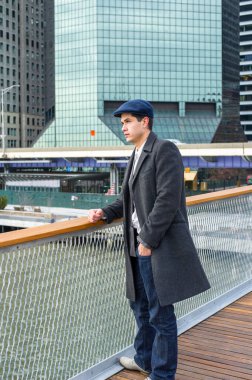 Genç bir profesyonel iş yerinin önünde duruyor ve etrafa bakıyor.