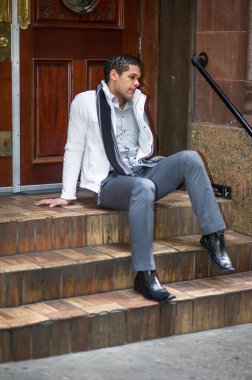 Genç bir adam kapının önünde oturuyor ve derin düşüncelere dalıyor.