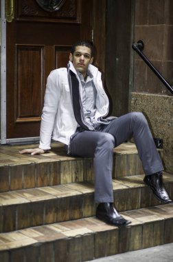 Genç bir adam kapının önünde oturuyor ve derin düşüncelere dalıyor.