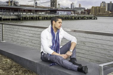 Genç bir öğrenci nehir kenarında oturuyor ve derin derin düşünüyor.