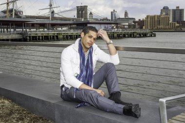 Genç bir öğrenci nehir kenarında oturuyor, kafasını kaşıyarak derin derin düşünüyor.