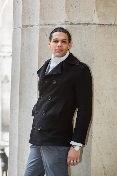 Büyük bir sütuna güvenerek, yakışıklı bir adam duruyor ve sana bakıyor.