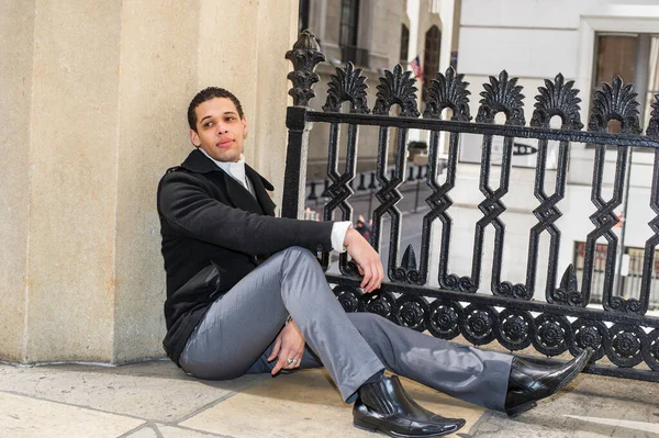 Genç bir üniversite öğrencisi yerde oturuyor ve dinleniyor.