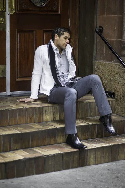 Genç bir adam kapının önünde oturuyor ve derin düşüncelere dalıyor.