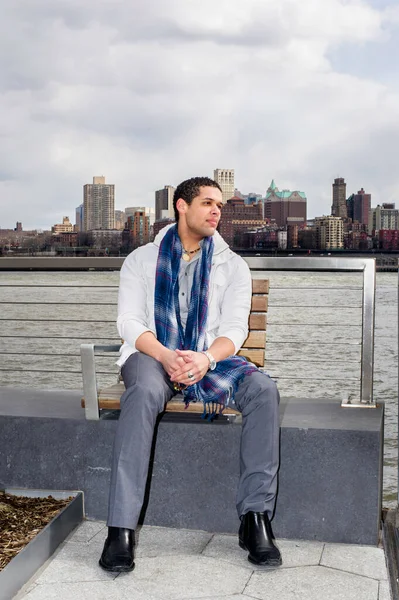 Büyük bir şehir sınırına karşı, genç bir öğrenci nehir kenarında oturuyor ve düşünüyor.