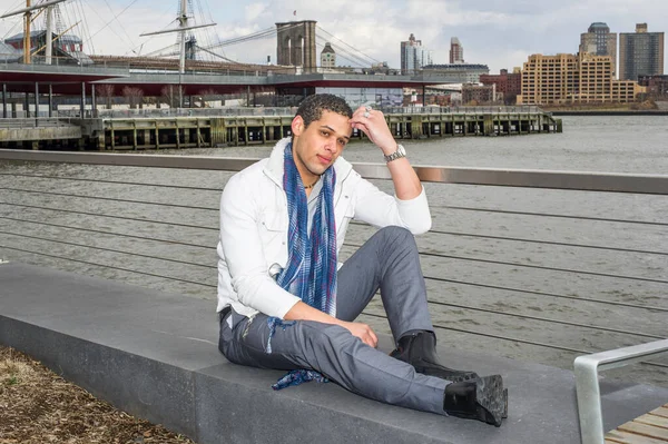 Genç bir öğrenci nehir kenarında oturuyor, kafasını kaşıyarak derin derin düşünüyor.