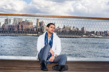 Büyük bir şehir sınırına karşı, genç bir adam rıhtımda oturuyor ve ciddi ciddi düşünüyor.