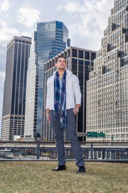 Genç bir profesyonel bir iş yerinin önünde duruyor ve umarım ileriye bakıyordur.