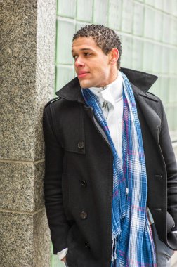 Duvara güvenerek, genç ve yakışıklı bir adam gözlerini kaçırıyor.