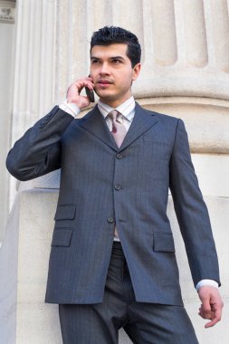 Genç bir işadamı dışarıda telefonla konuşuyor.