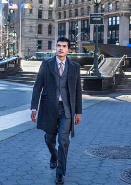 Genç bir işadamı kendinden emin bir şekilde dışarıda yürüyor.