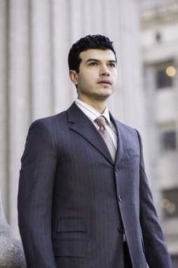 Resmi olarak giyinmiş genç bir işadamı dışarıda bekliyor.