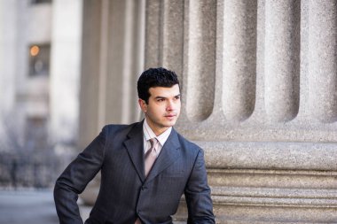 Resmi olarak giyinmiş genç bir işadamı dışarıda bekliyor.
