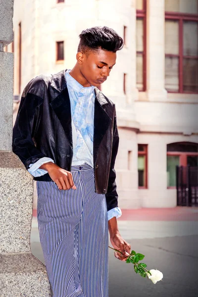 Yalnız çocuk. 18 yaşında bir öğrenci, şık siyah bir ceket, çizgili pantolon, mavi-boyanmış beyaz gömlek giyiyor, elinde beyaz bir gül, üzgün, düşünceli bir şekilde kampüsün kapısında duruyor..