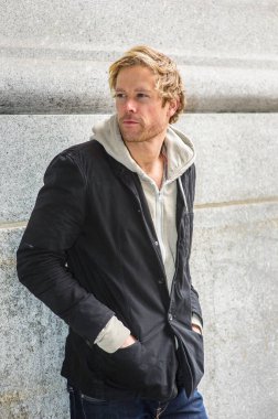 Genç ve yakışıklı bir adam dışarıda durup düşünüyor.