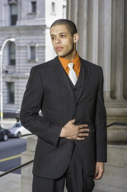 A young businessman is standing in the front of office building and into deeply thinkin