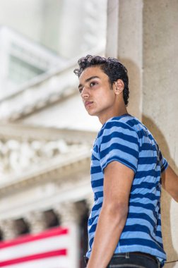 Mavi çizgili tişört giyen Asyalı genç, kendinden emin bir şekilde ileriye bakıyor.