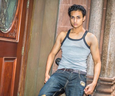 Bir atlet, şık bir pantolon, genç bir Asyalı genç kapı eşiğine eğiliyor ve sana bakıyor.