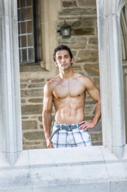 Genç, yakışıklı, kaslı bir adam eski moda bir vitrinden bakıyor..