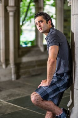 Genç yakışıklı bir adam pencerenin önünde dikiliyor ve ileriye bakıyor..