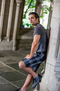 Genç yakışıklı bir adam pencerenin önünde dikiliyor ve ileriye bakıyor..