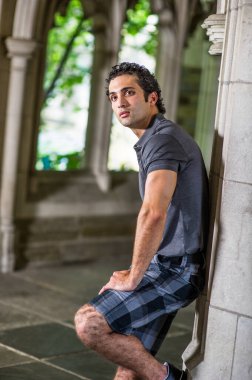 Genç yakışıklı bir adam pencerenin önünde dikiliyor ve ileriye bakıyor..