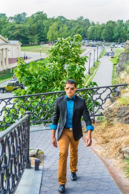 Siyah ceket, mavi gömlek, kahverengi pantolon ve siyah papyon takan, güneş gözlüğü takan genç ve yakışıklı bir adam,.