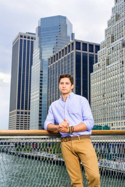 Açık mavi gömlek ve koyu sarı kot pantolon giyen genç ve yakışıklı bir adam bir iş yerinin önünde duruyor ve şöyle düşünüyor:.