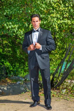 Profesyonel bir yönetici siyah bir smokin giyip, kendinden emin bir şekilde sana bakıyor..