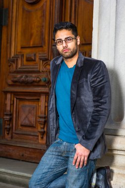 Koyu mor yün ceket, kazak ve kot pantolon giyen, gözlük takan, ekmek ve bıyıklı genç bir alim nedense kapının önünde duruyor, ciddi ciddi sana bakıyor ve seni dinliyor.