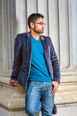 Koyu mor yün ceket, kazak ve kot pantolon giyen, gözlük takan, ekmek ve bıyıklı genç bir alim, bir sütunun yanında durup, derin düşüncelere dalmaktır.