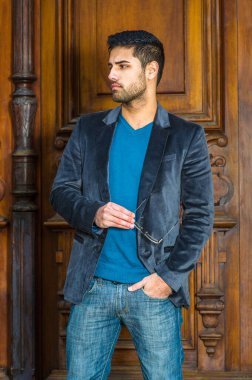 Mavi yün bir ceket, örgü süveter ve kot, gözlük ve kırmızı bir kitap giymiş, ekmek ve bıyıklı genç yakışıklı bir profesör kapıda bekliyor, gülümseyerek ileriye bakıyor.