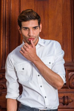 Genç adamın portresi. Beyaz gömlek giyen genç bir üniversite öğrencisi, eski moda ofis kapısının yanında duruyor, kolunu kaldırıyor, başparmağı dudağa değiyor, derin düşüncelere dalıyor.