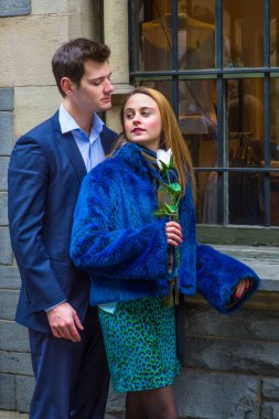 Beyaz bir gül tutan, çekici genç bir çift tutkuyla birbirlerine bakıyor