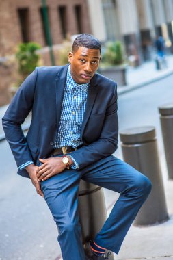 Genç bir siyah işadamı sokakta oturuyor ve nefes alıyor.