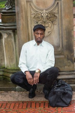 Yağmurda, genç yakışıklı siyah bir gezgin orada çömeliyor ve derin düşüncelere dalıyor