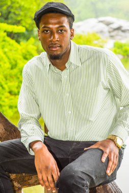 Yağmurlu bir gün, biraz sisli, ıslak bir his. Uzun kollu bir gömlek, sarmaşık bir şapka, genç yakışıklı siyah bir adam, yağmurlu, sisli bir günde gölün kenarında oturuyor ve büyüleyici bir şekilde sana bakıyor..