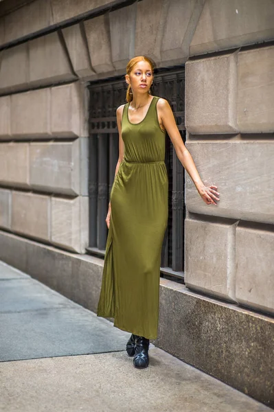 Girl Waiting For You. Dressing in a green, long Maxi Tank Dress,  black dress sandals, a young black woman is standing by old fashion style window and wall, passionately looking forward
